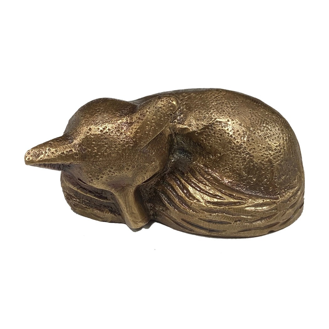 Bronze figurine of a dog lying down on a white background