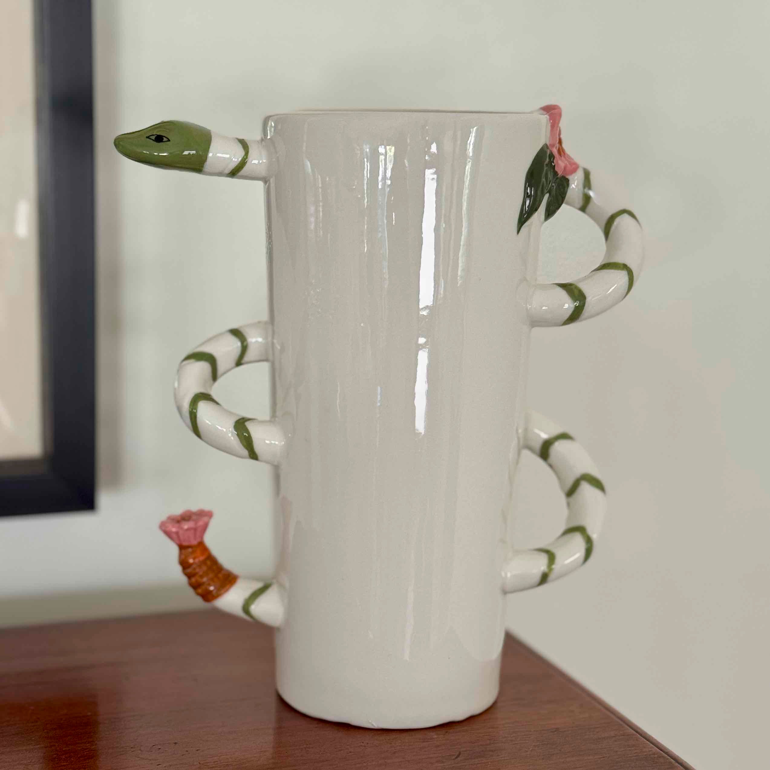 White mug with a snake-shaped handle on a wooden surface