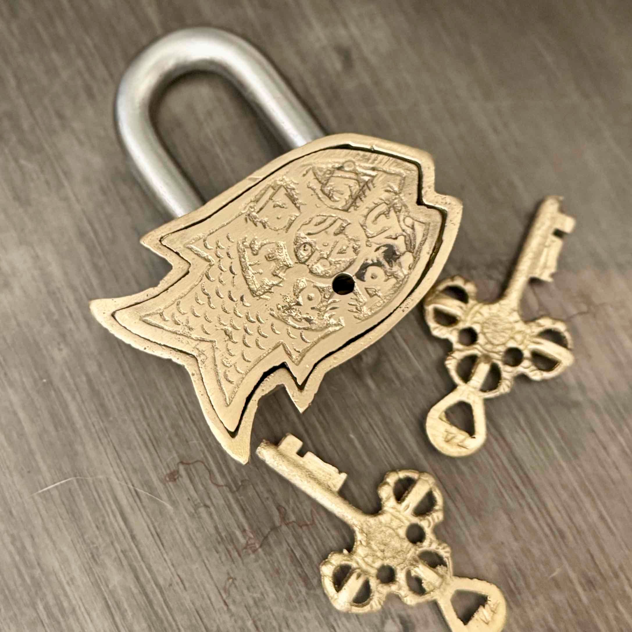 Decorative brass padlock with two keys on a wooden surface