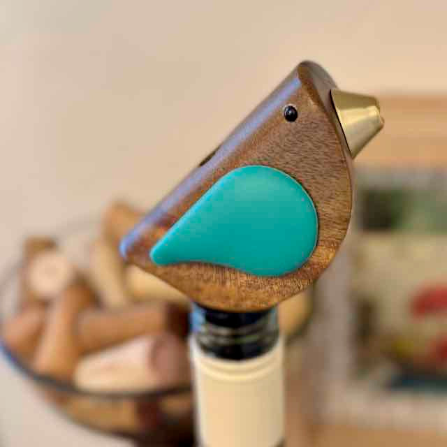 Wooden bird-shaped bottle stopper on a bottle with blurred background