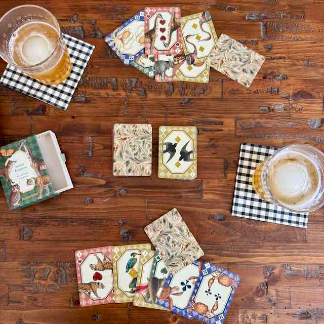 Set of decorative coasters with animal illustrations on a wooden table with drinks.