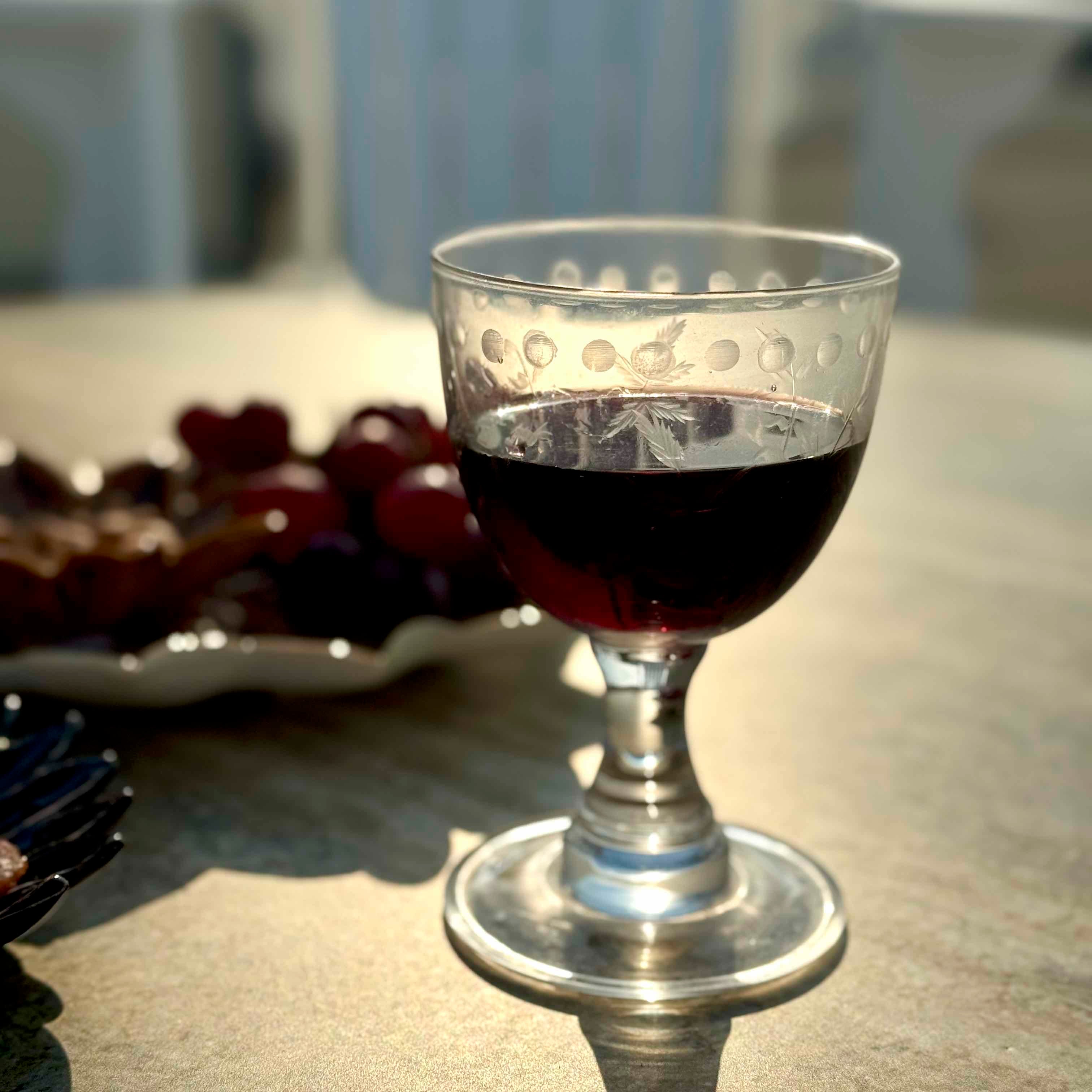 Glass of red wine on a table with grapes in the background