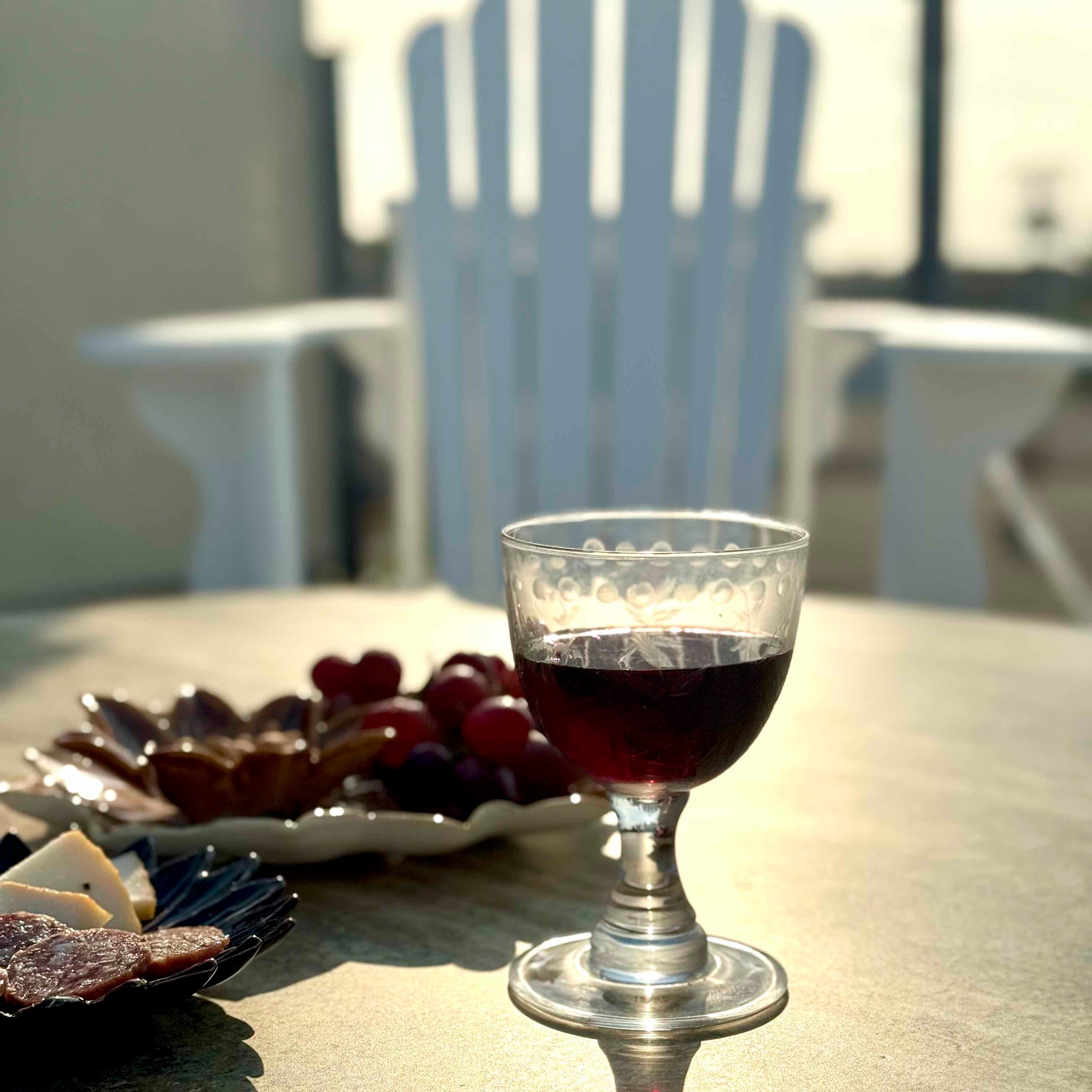 Glass of red wine on a table with cheese and grapes, outdoor setting