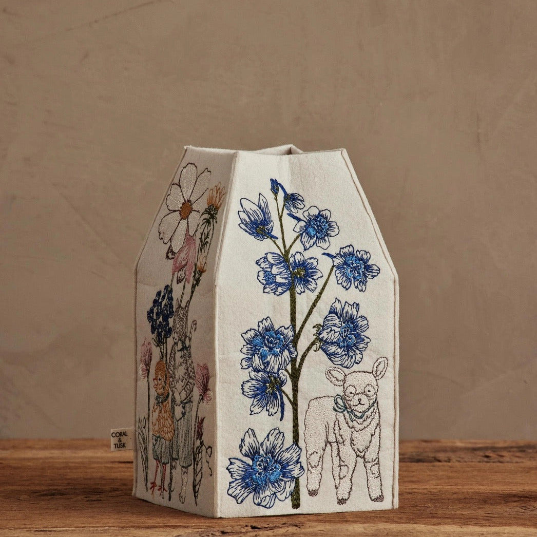 Decorative milk carton with floral and animal illustrations on a wooden surface.