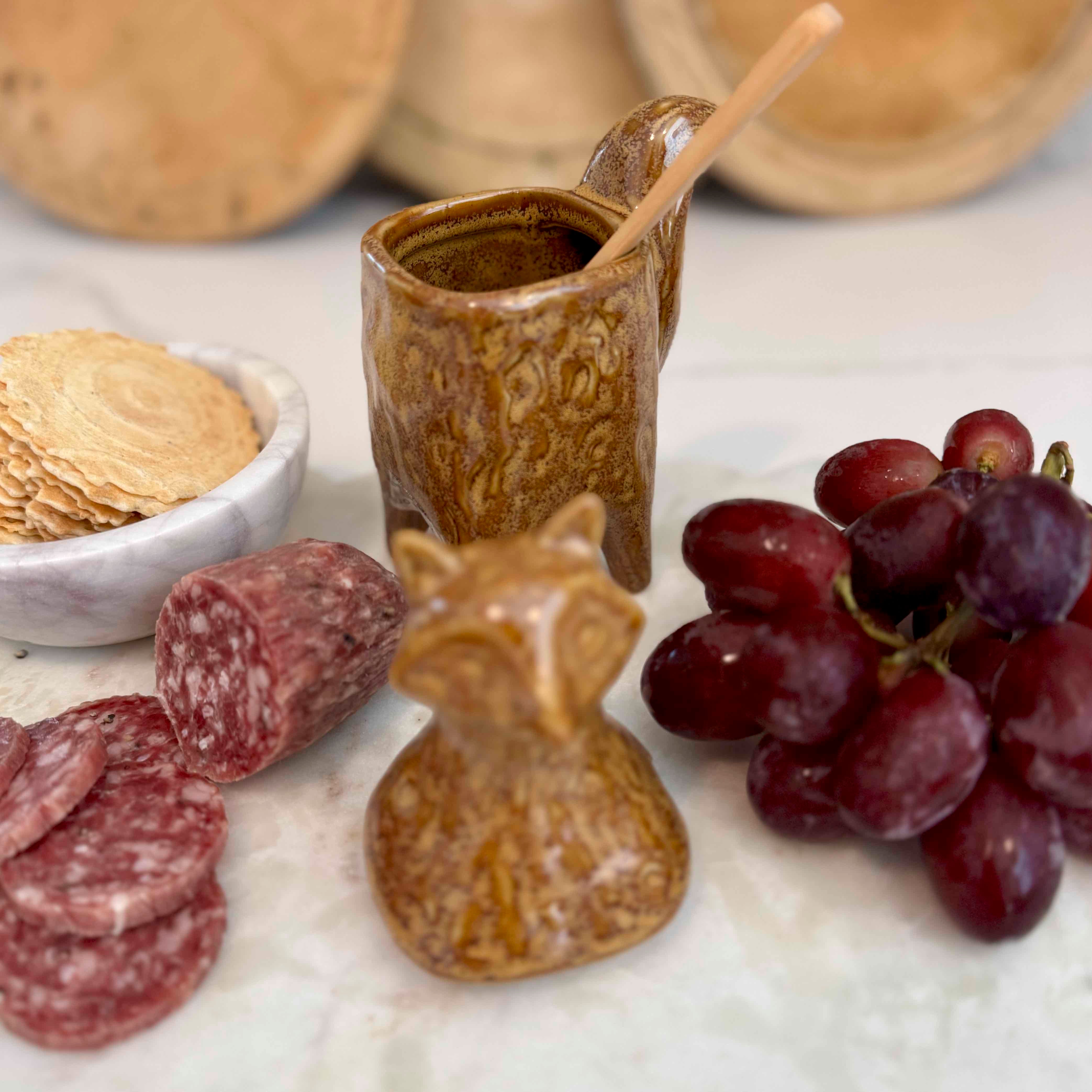 Ceramic fox-shaped container with snacks and fruits on a marble surface