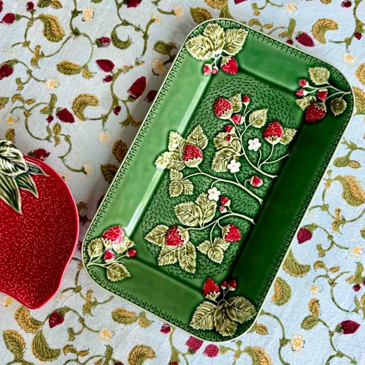Decorative green tray with floral and berry designs on a patterned fabric background