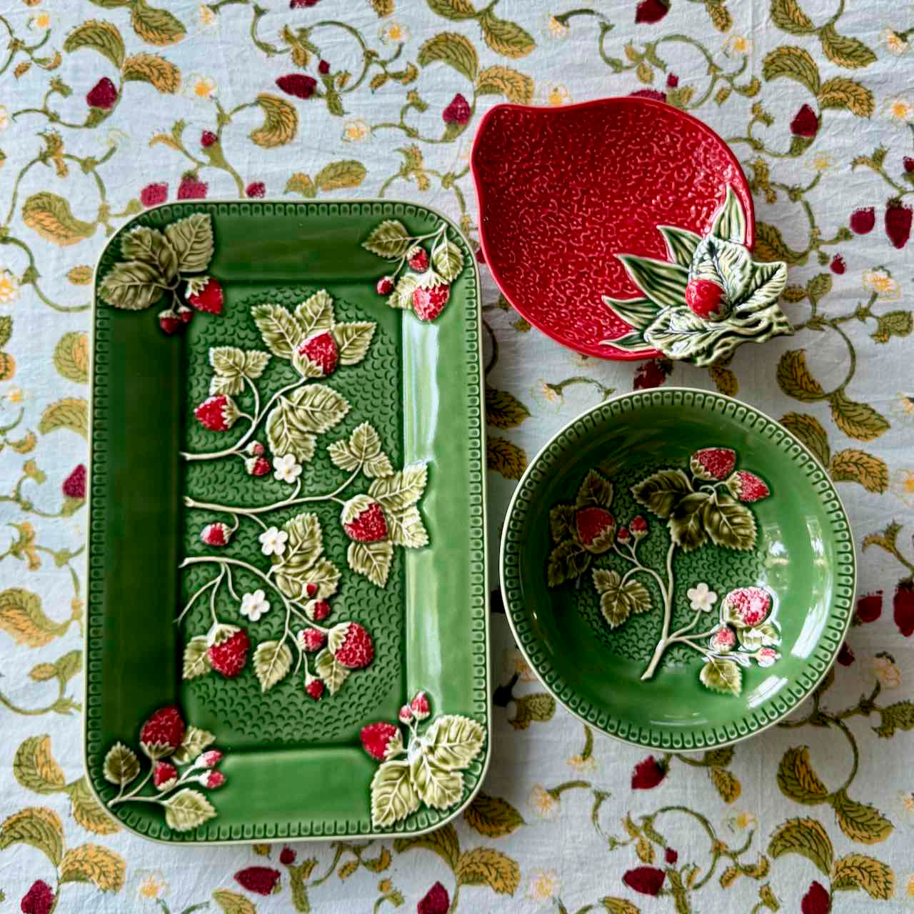 Decorative ceramic plates with floral and berry design on a patterned fabric background