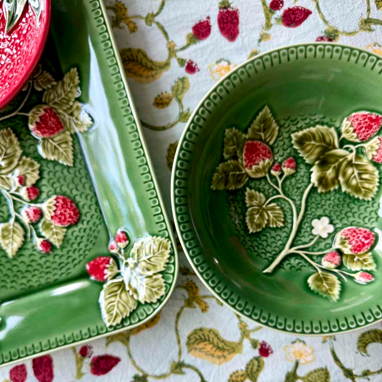 Green ceramic plates with floral designs on a patterned fabric background