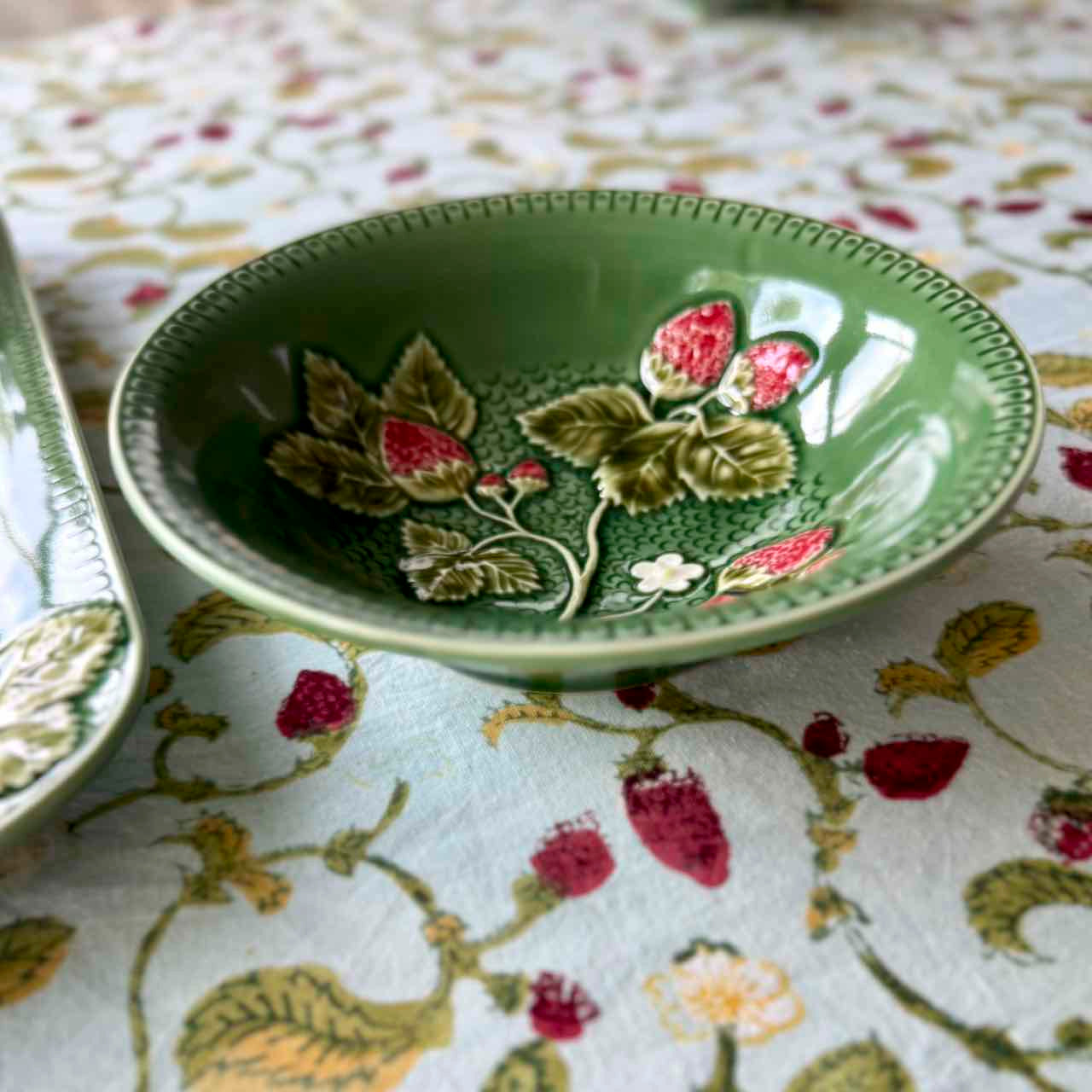 Green ceramic dish with floral design on a patterned tablecloth