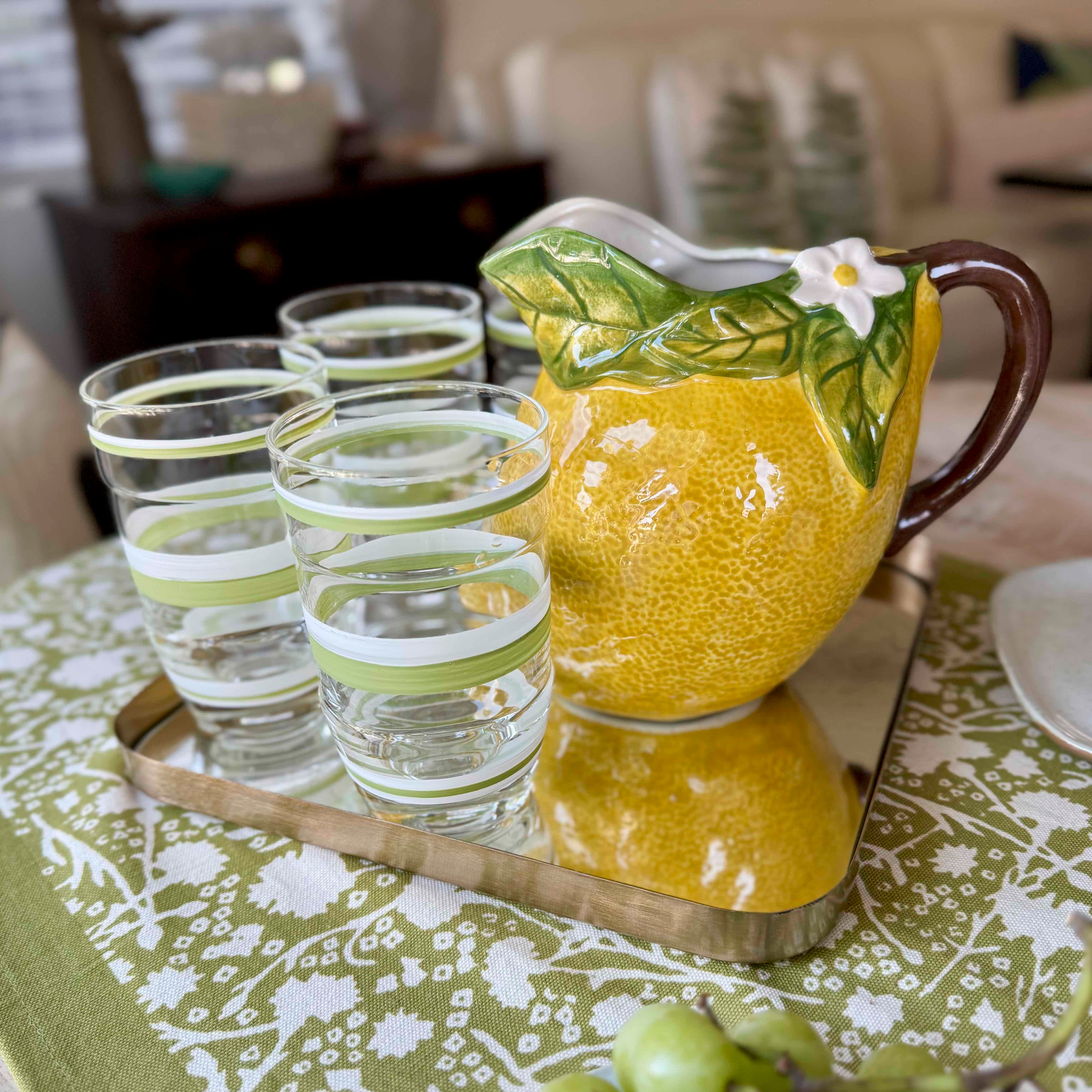 Yellow ceramic pitcher with floral design on a floral tablecloth