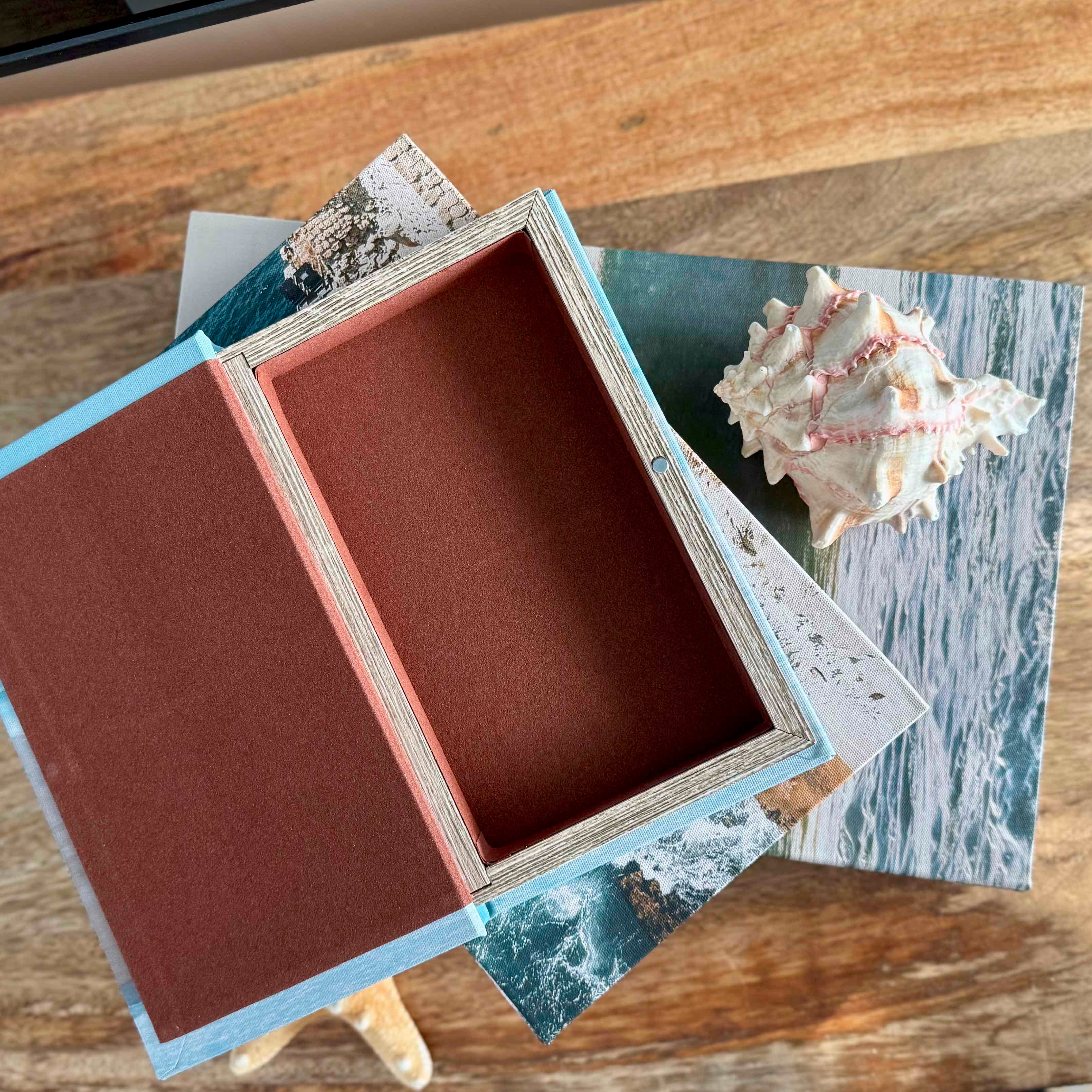 Open jewelry box with a shell and card on a wooden surface