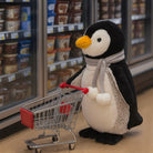 Plush penguin toy with a shopping cart in a grocery store setting