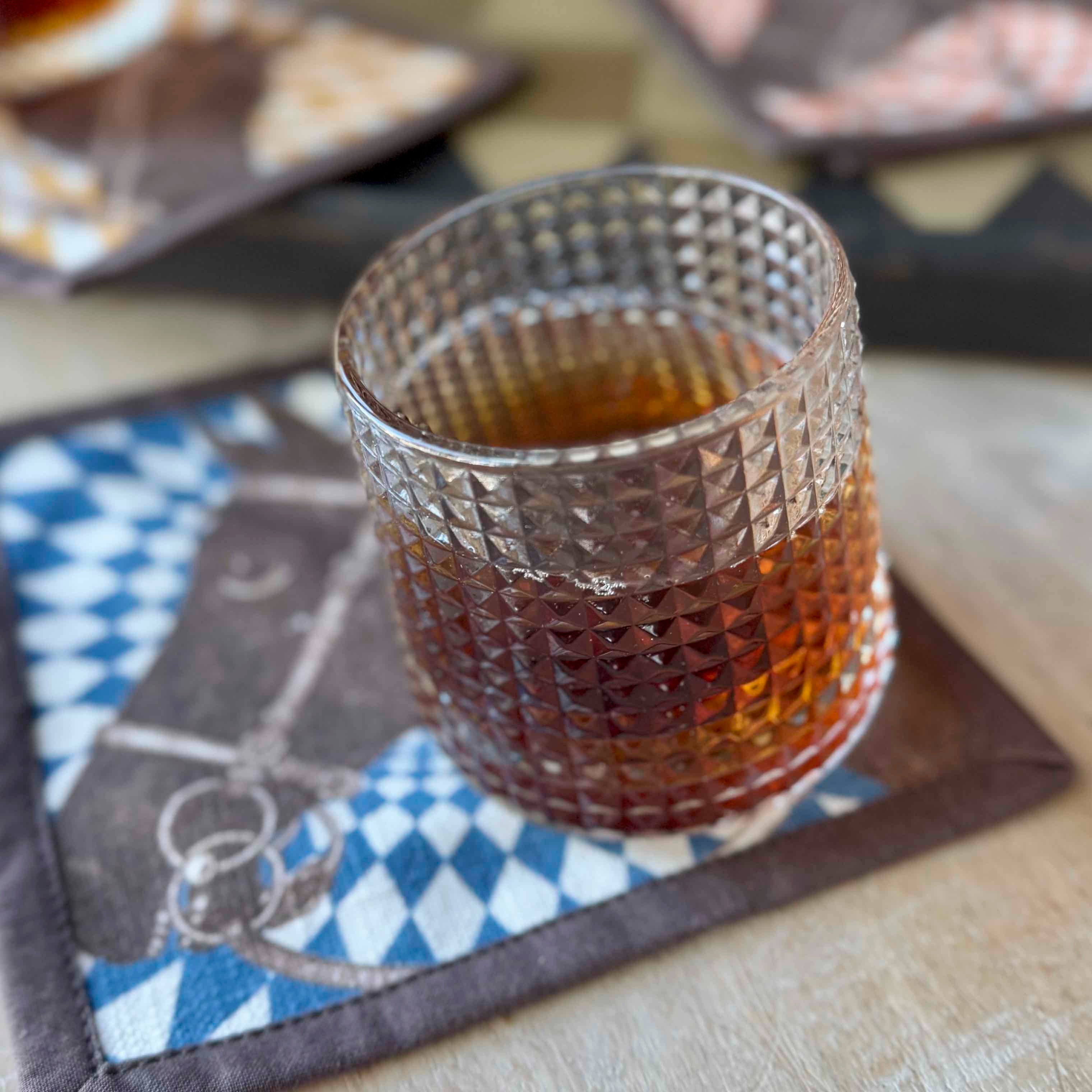 Glass of amber liquid on a decorative napkin with blurred background