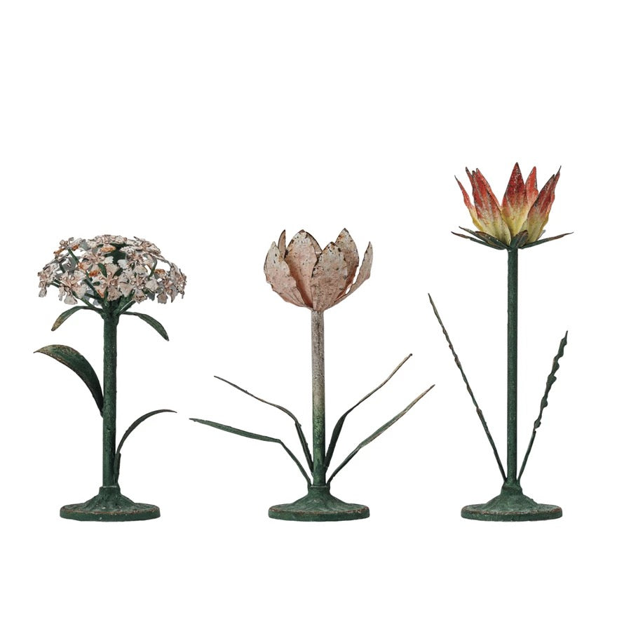 A set of three vintage-inspired metal flower candleholders in different designs, with a distressed multicolor finish.