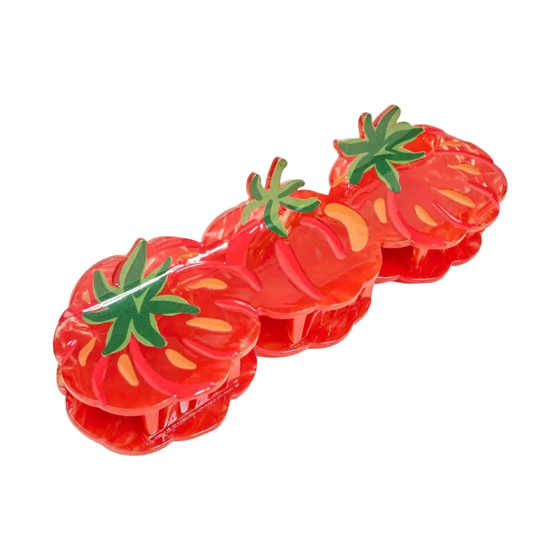 Three red strawberry-shaped hair claw clips with green leafy tops and yellow inner details, arranged diagonally on a light beige background.