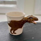 Ceramic mug with a dinosaur design on a dark surface