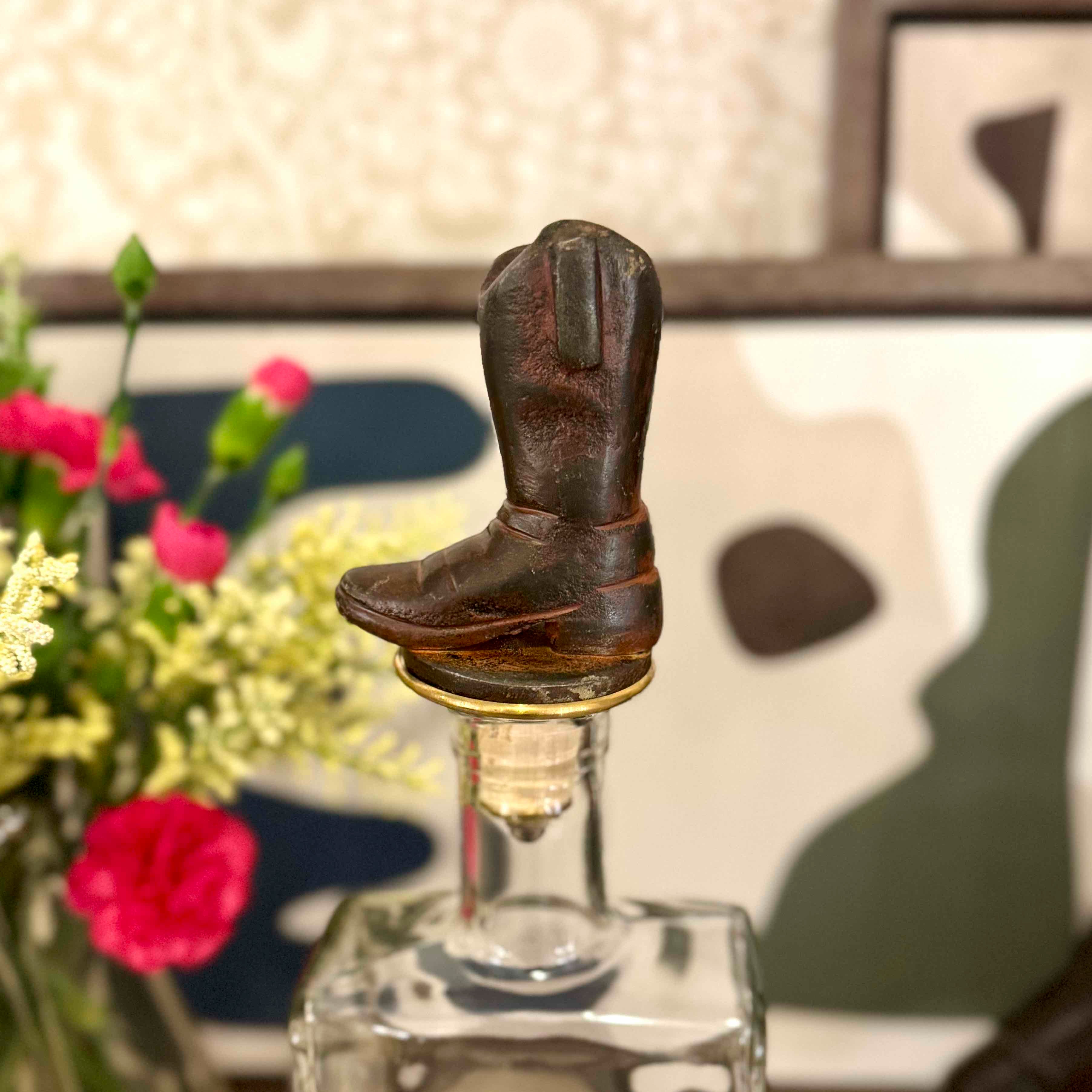Decorative light bulb with cowboy boots on top, surrounded by flowers.