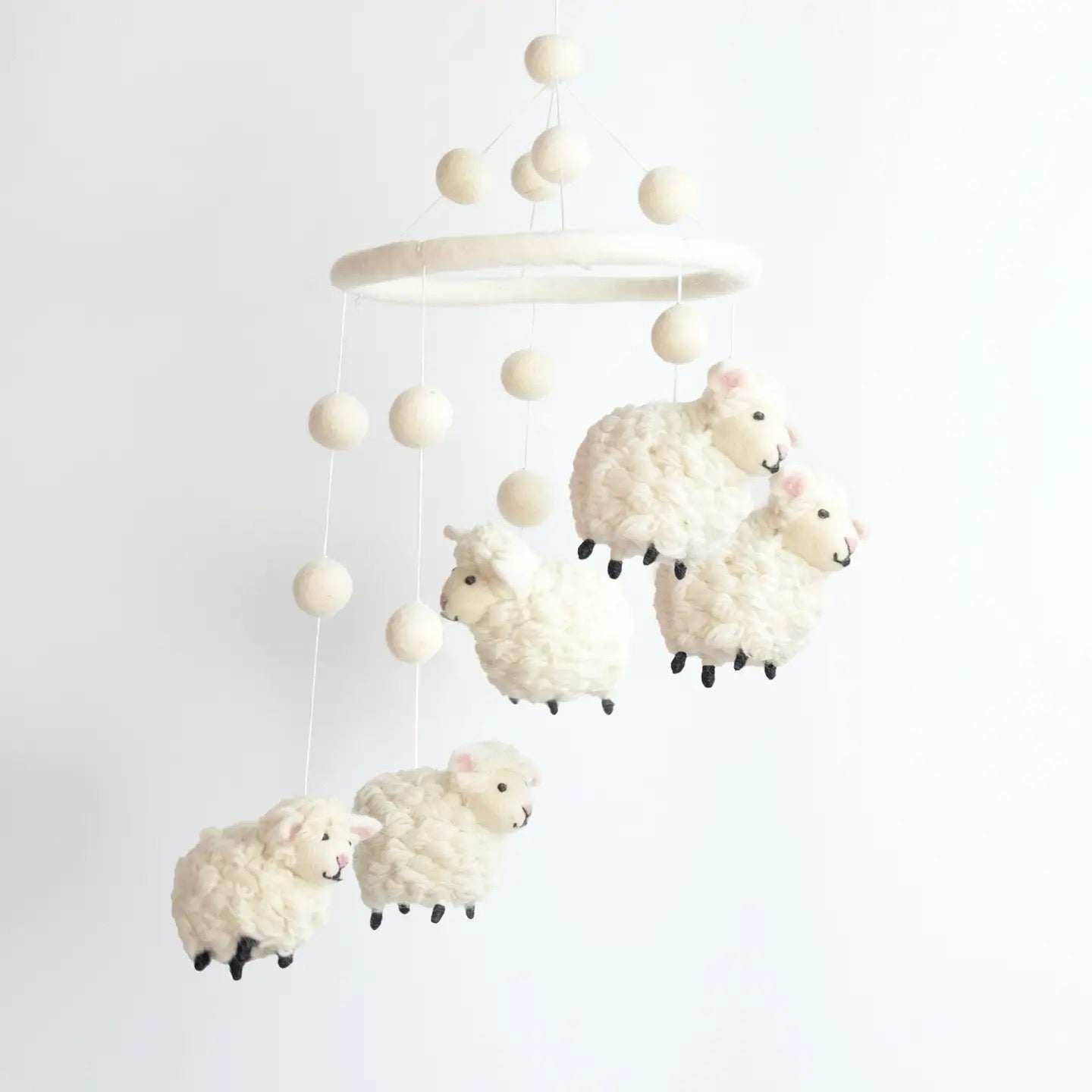 Baby mobile with sheep toys hanging from a wooden ring on a white background