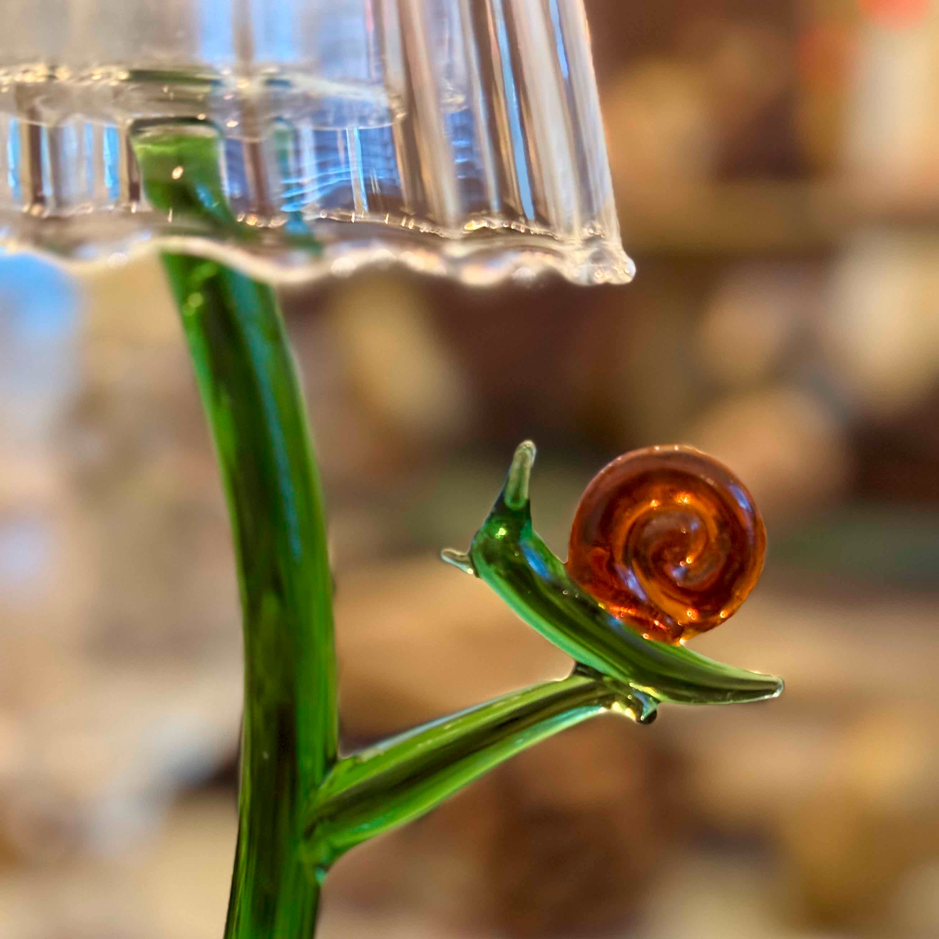 Glass snail on a green stem with a blurred background