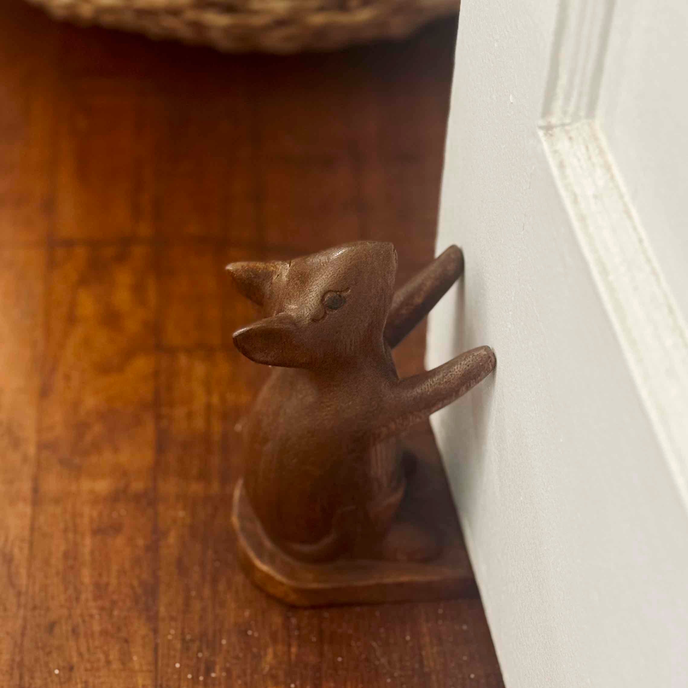 Wooden fox figurine on a wooden surface next to a white door