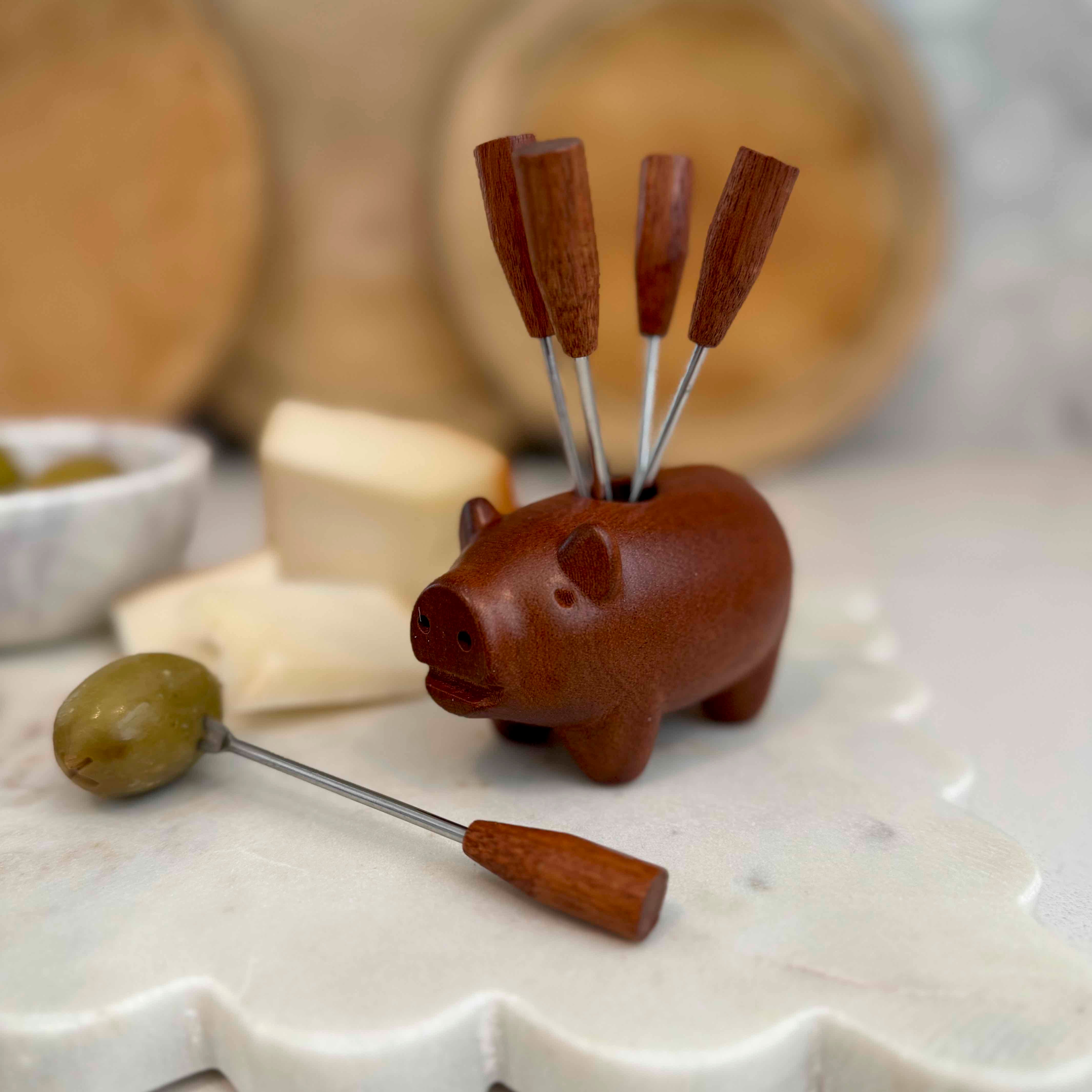 Pig-shaped olive pick with olives on a decorative plate