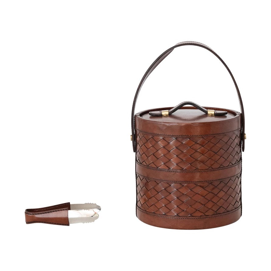 Brown woven leather ice bucket with handle and tongs on a white background