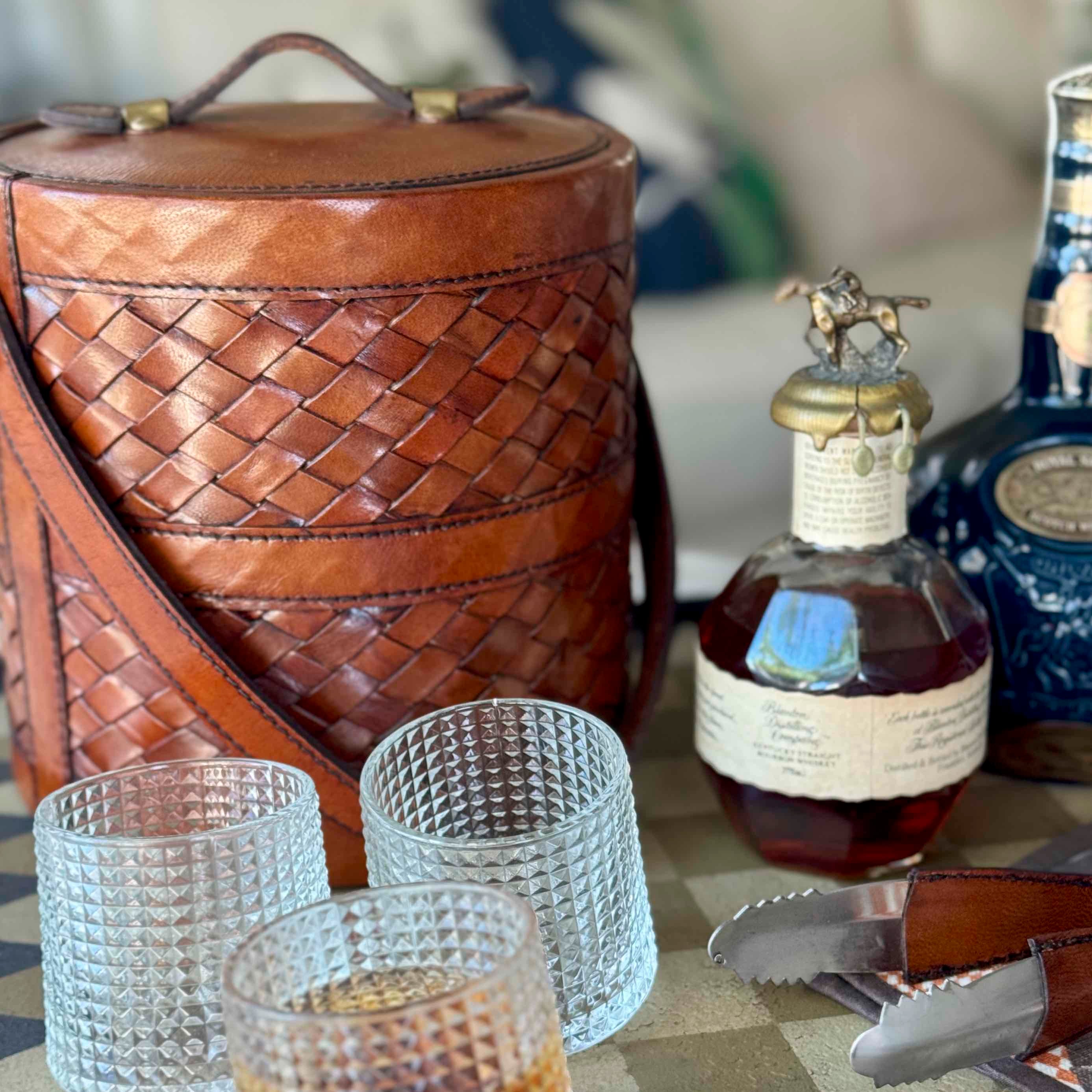 Bottle of Johnnie Walker Blue Label whisky with a leather cooler and glasses on a table.