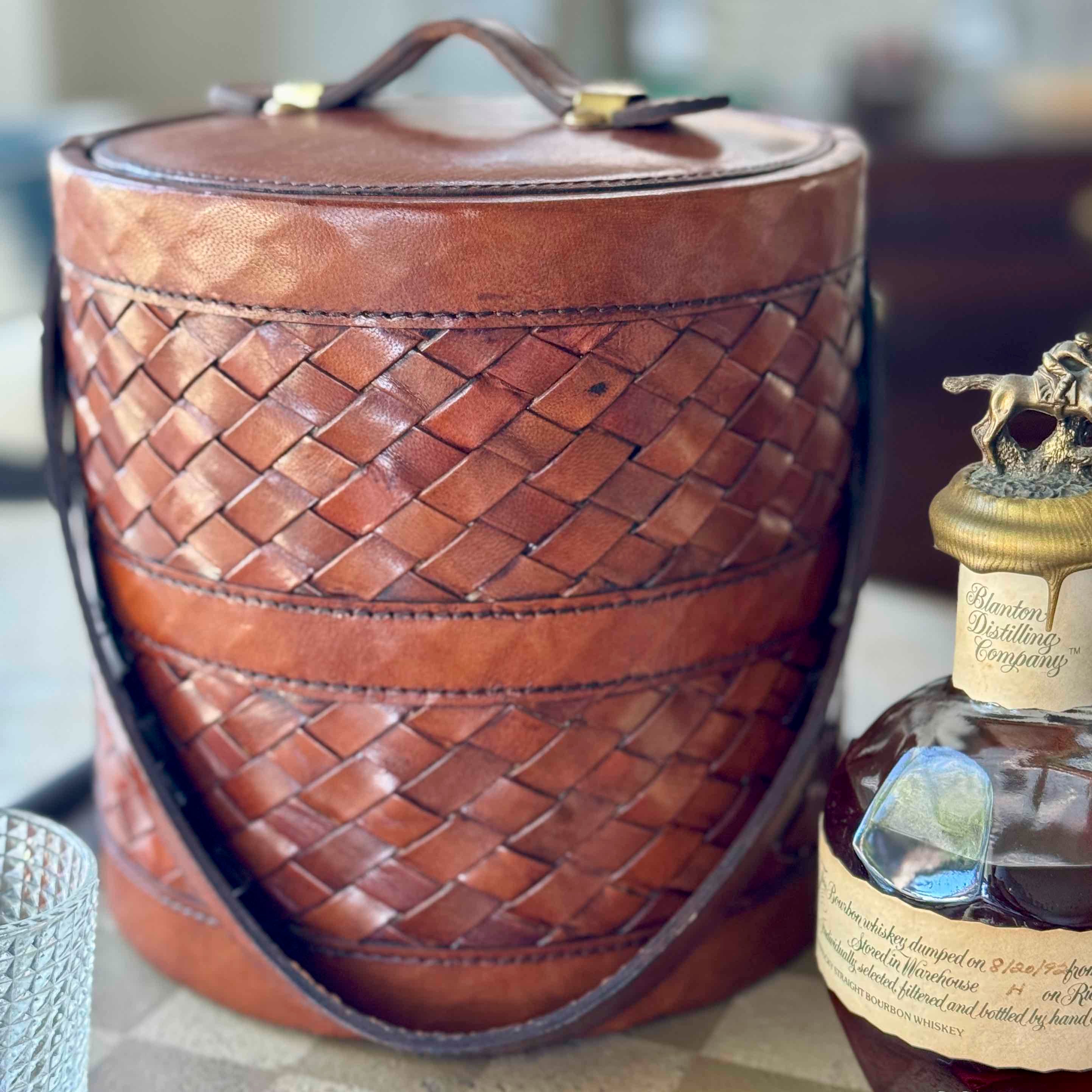 Brown woven leather hat box with a bottle of Johnnie Walker Blue Label whisky.