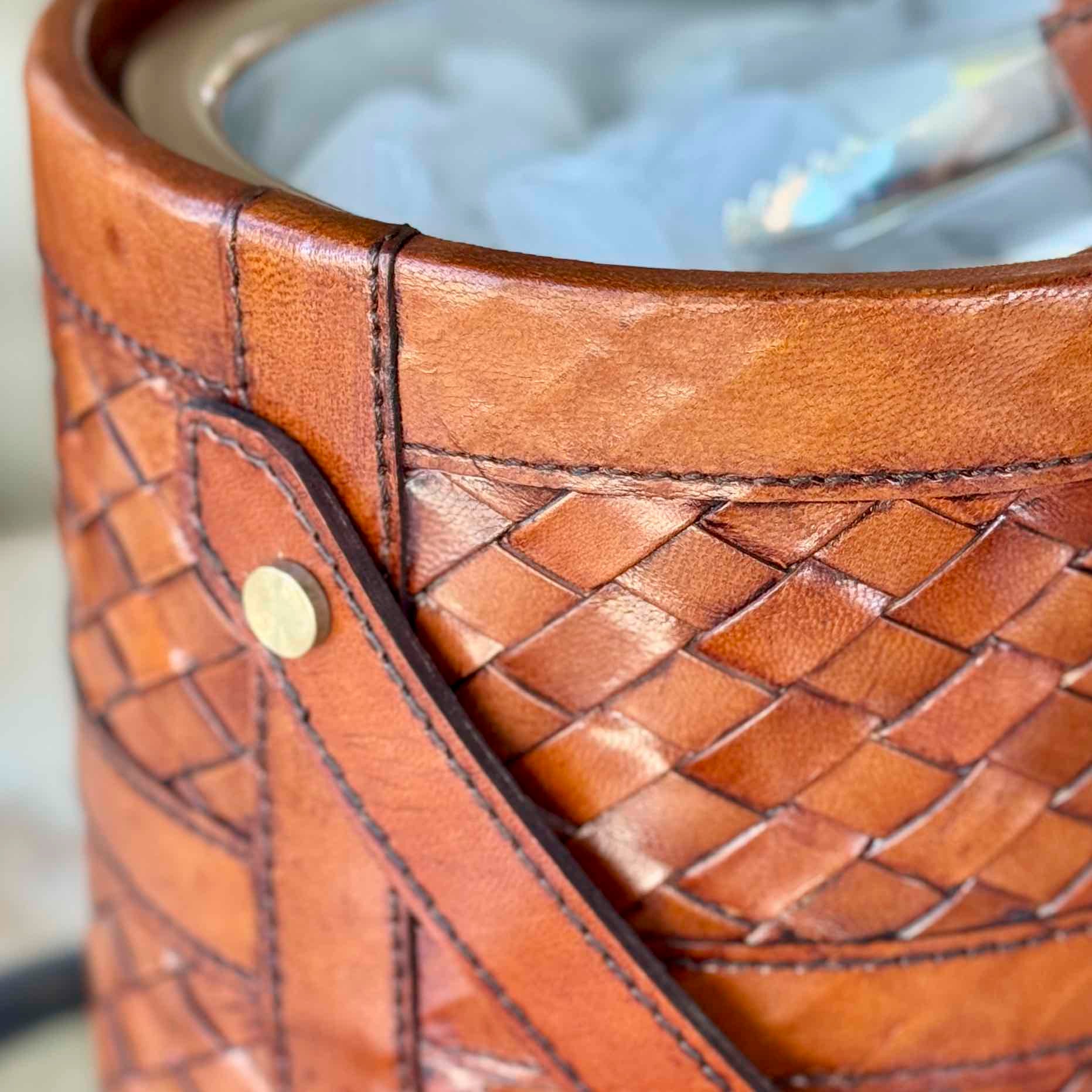 Close-up of a brown leather basket with woven pattern and metallic button.