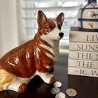 Corgi dog-shaped piggy bank with coins on a surface