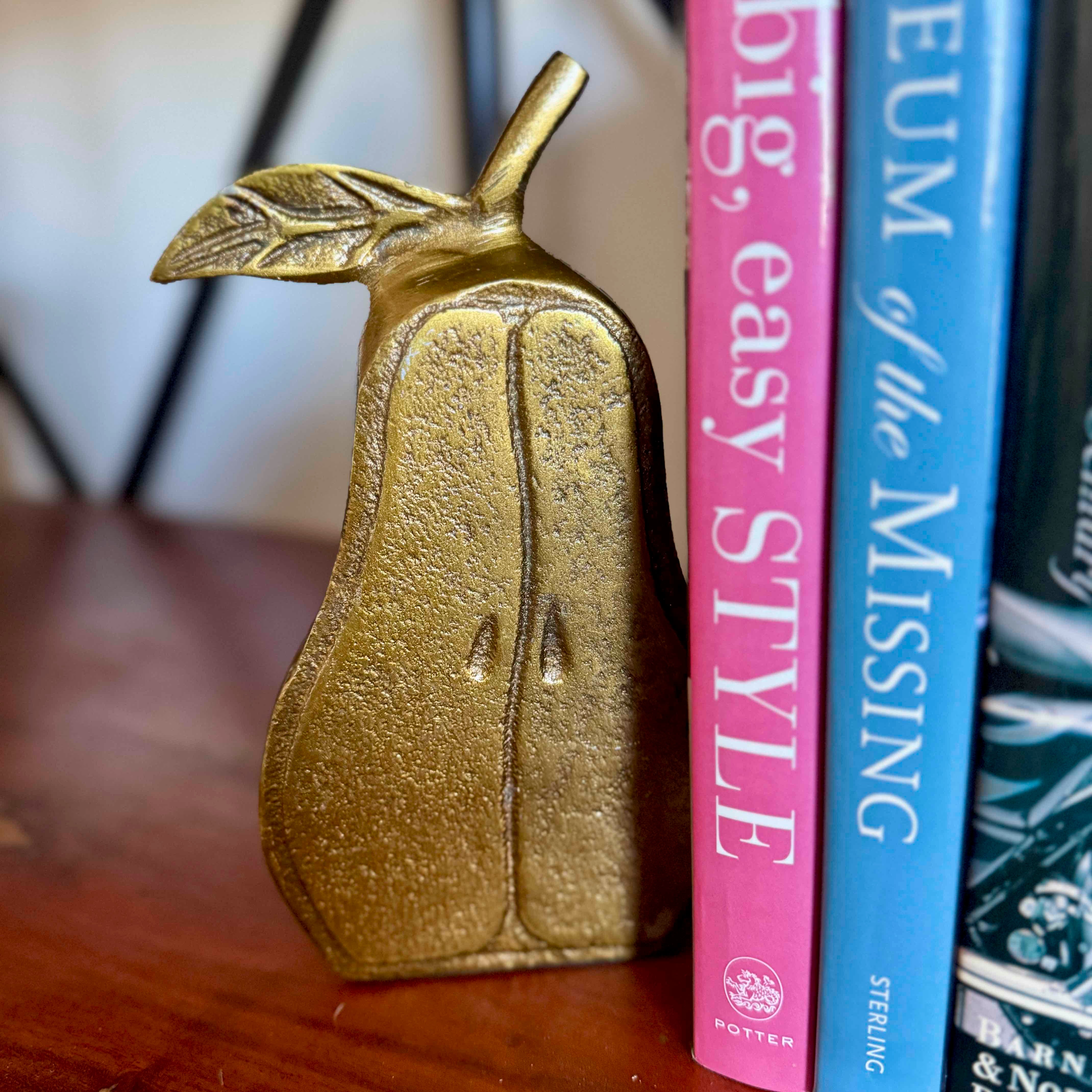 Gold pear-shaped object next to books on a wooden surface