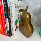 Gold pear-shaped object on a shelf with cookbooks in the background