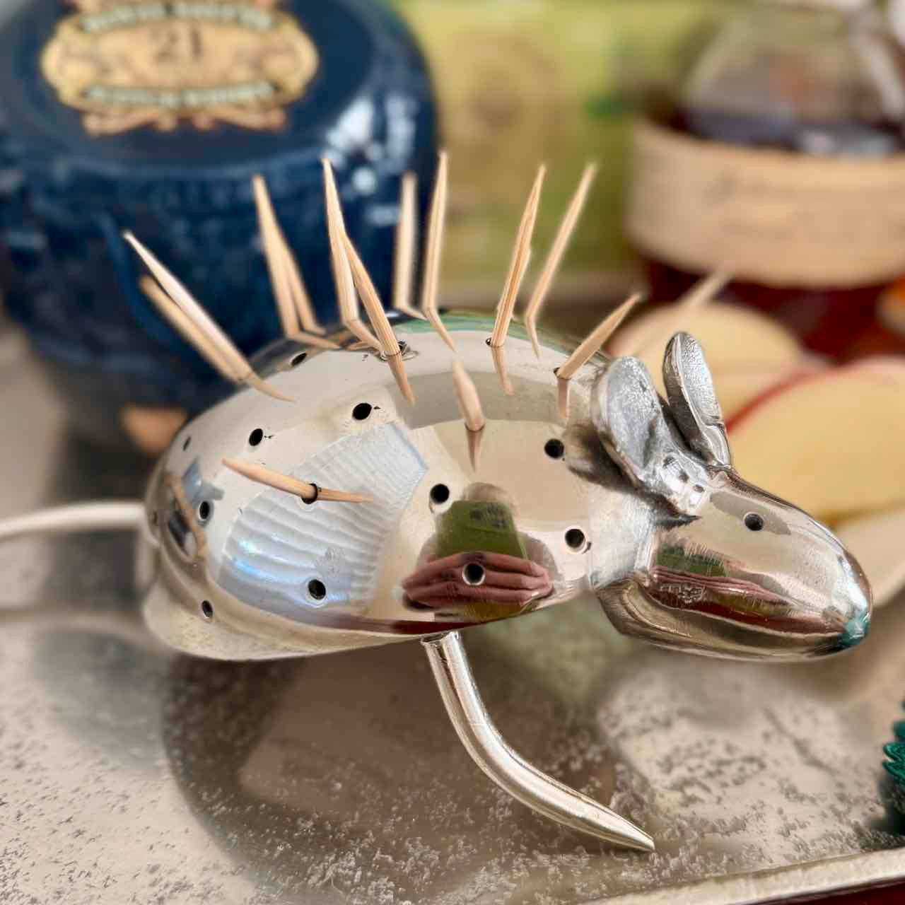 Metallic moose-shaped toothpick holder with toothpicks on a reflective surface.