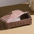 A rectangular ceramic box with a matching lid, featuring a textured terracotta-brown and beige speckled glaze, set on a light wooden surface.