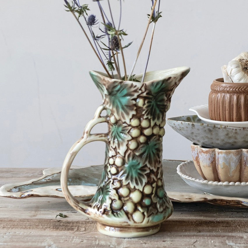 Ceramic pitcher with decorative patterns on a wooden surface