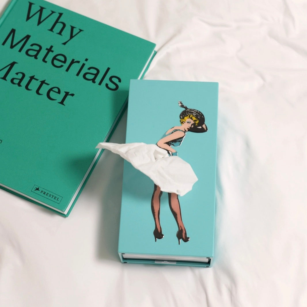 Two books on a white surface, one titled 'Why Materials Matter' and the other with an illustration of a woman in a white dress.