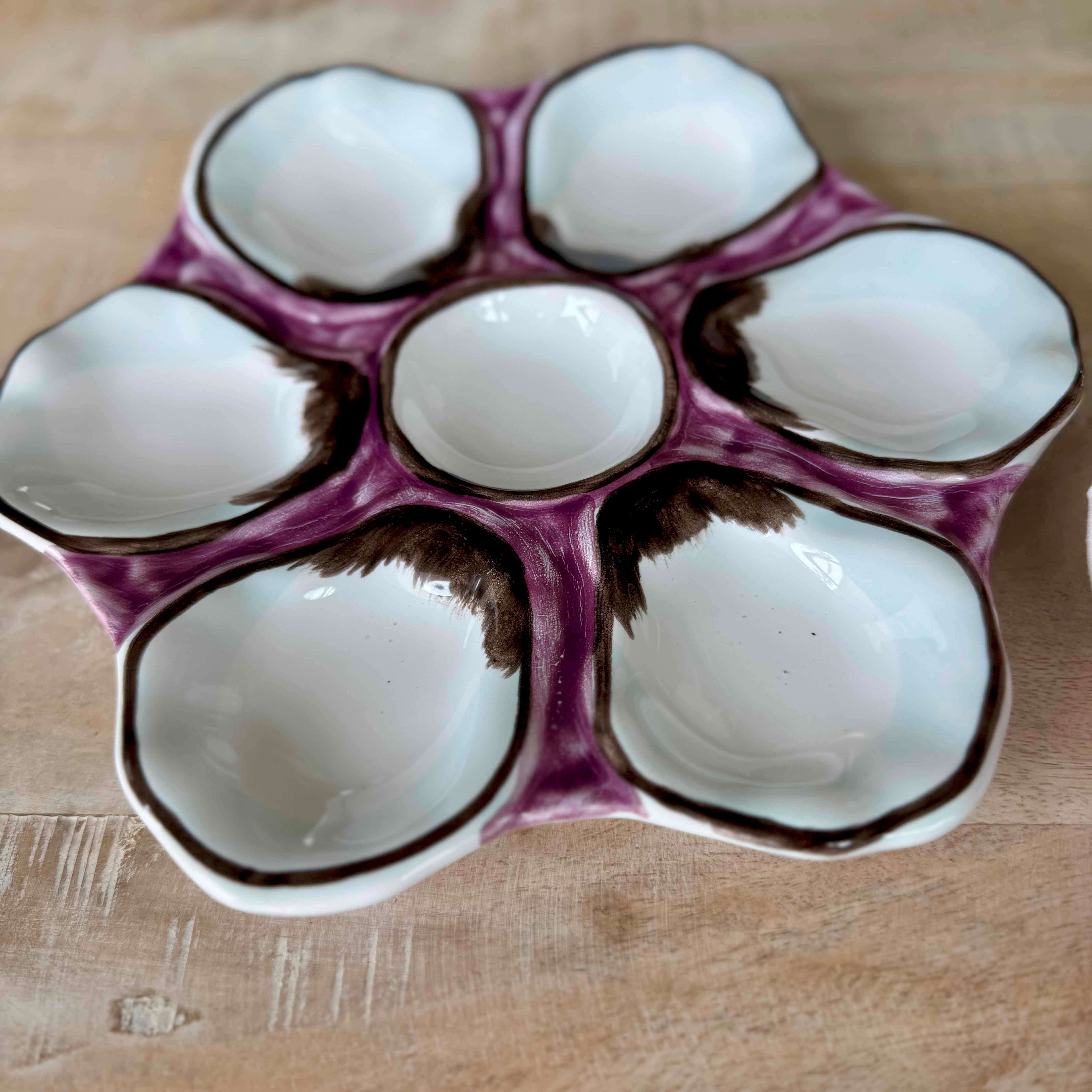 Decorative ceramic egg tray with purple rim on a wooden surface