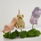 Three ceramic animal figurines on green spherical bases with a white background