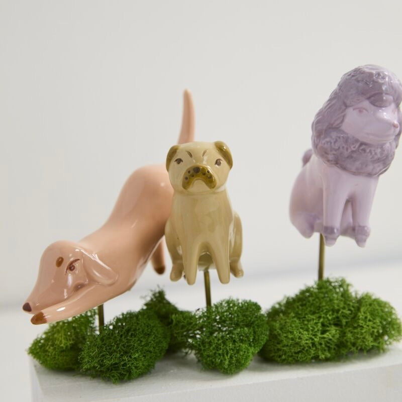 Three ceramic animal figurines on green spherical bases with a white background