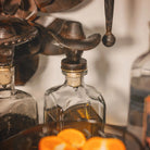 Decorative bottle with cowboy hat stopper and oranges in the foreground