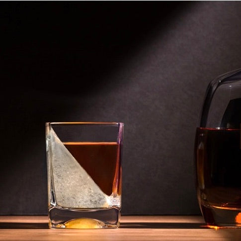 Two glasses of whiskey on a wooden surface with a dark background