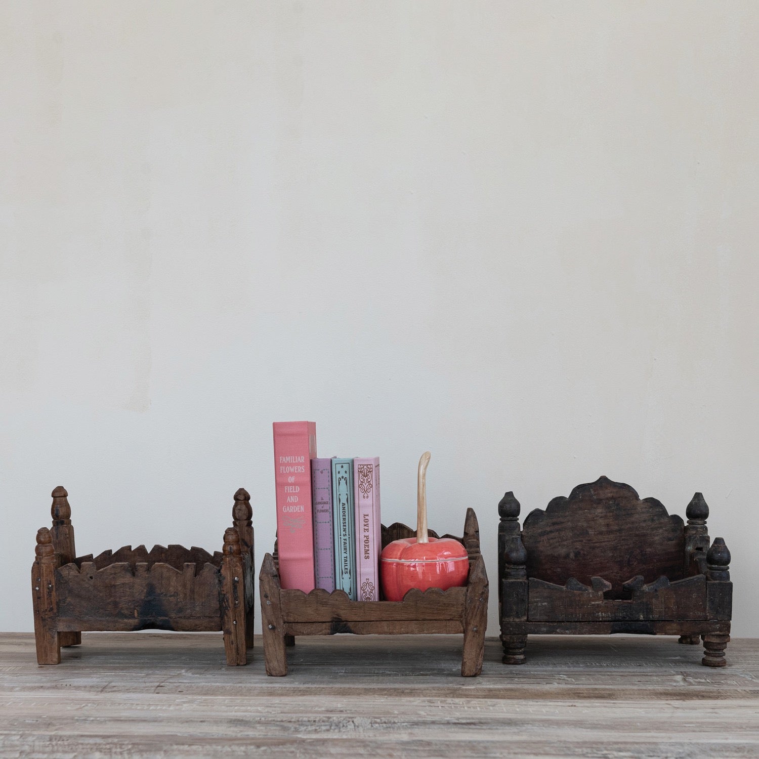 Wooden bookends with books and a decorative item on a wooden surface against a light gray wall.