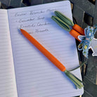 Notebook with Easter brunch menu and carrot-shaped pen on a table