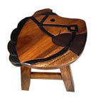 A small wooden stool shaped like a horse head, with a warm medium-brown wood finish and dark brown to black painted details outlining the horse face and mane, set against a plain white background.