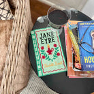 Book titled 'Jane Eyre' next to a glass of red wine on a table.
