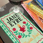 Book cover of 'Jane Eyre' with a glass of wine and books in the background