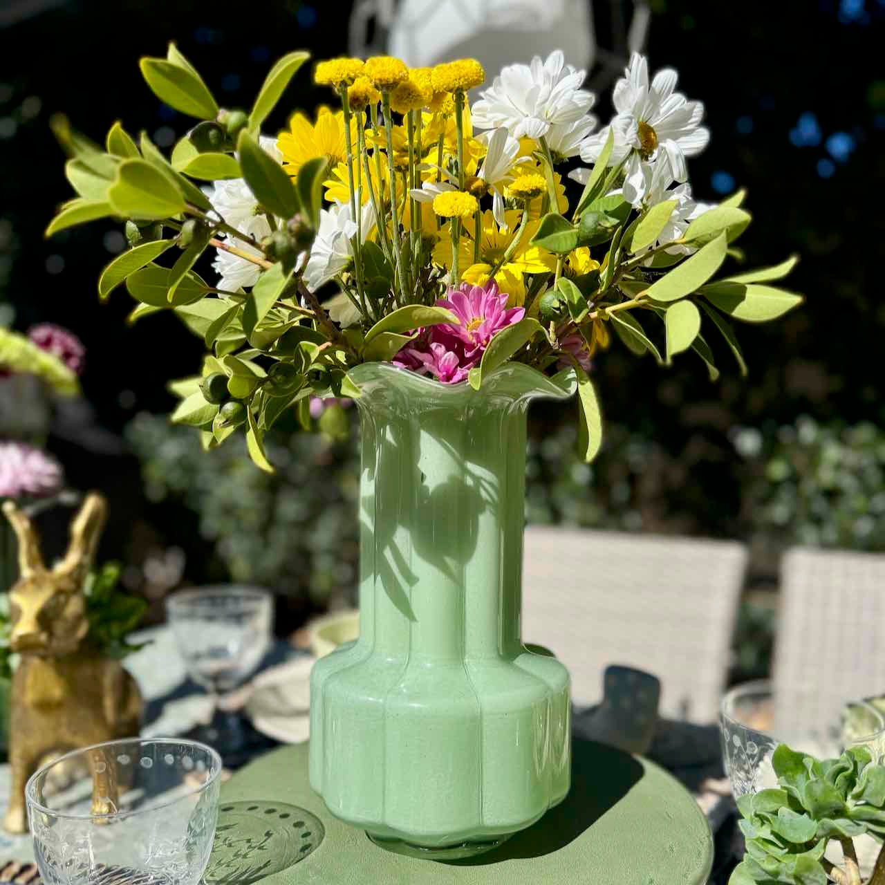 Green vase with flowers on a table outdoors
