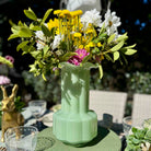 Green vase with flowers on a table outdoors