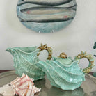 Decorative shell-shaped teapot and pitcher with a seashell on a neutral background