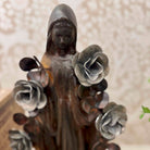 Statue of a woman with flowers in her hands against a neutral background